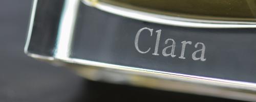 Gravur des Namens "Clara" auf dem Boden eines Parfümflakons aus transparentem Glas
